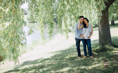 pregnant couple hugging by water