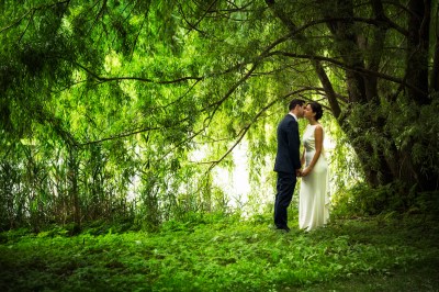 bride & groom kissing below tree