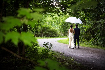 bride & groom walking under umbrella